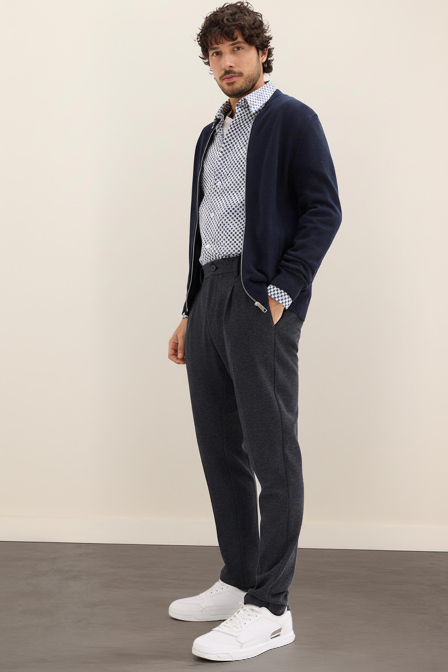 Marineblaue Strickjacke, gemustertes Hemd und graue Hose. 