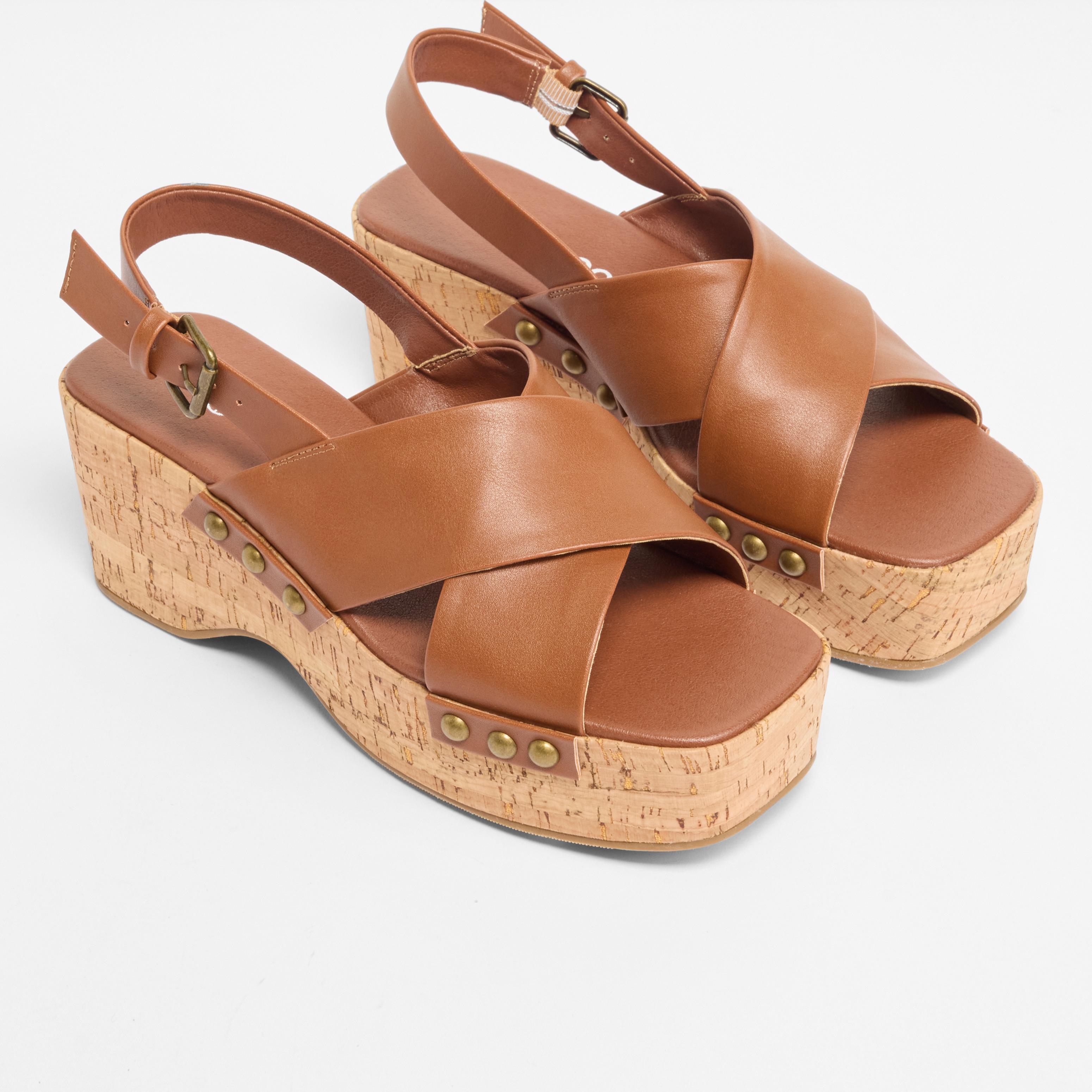 Braune Ledersandalen mit Korkabsatz und gekreuzten Riemen.