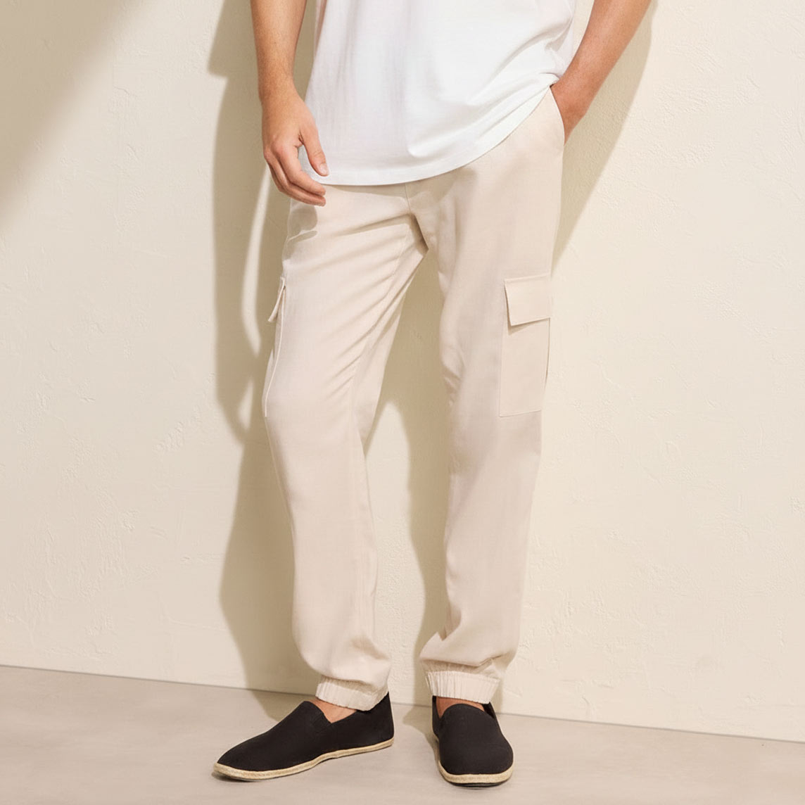 Lässiger Look mit weißem T-Shirt, beigen Cargohosen und dunklen Slip-on Schuhen.