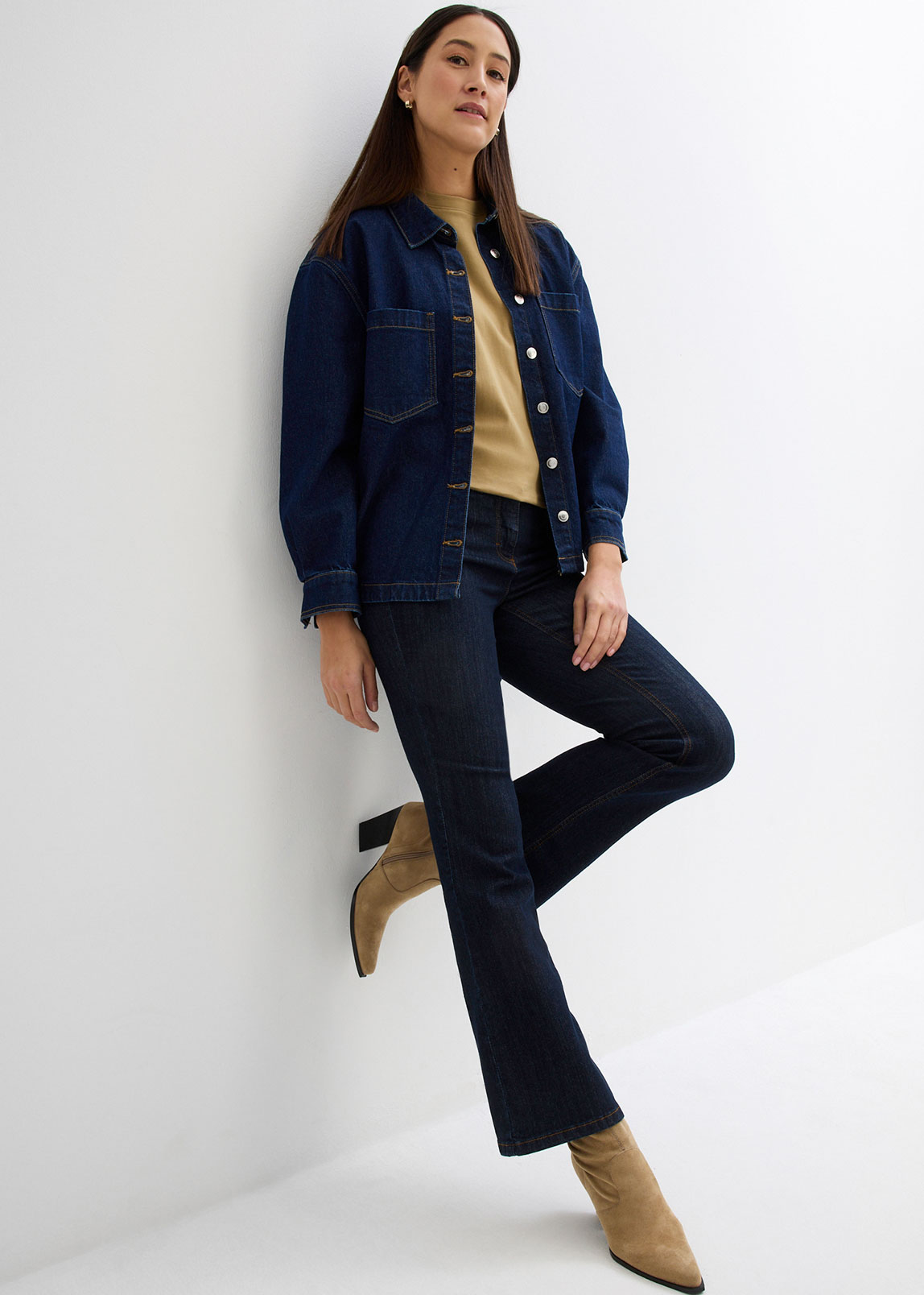 Dunkelblaue Jeansjacke und Jeans, beiger Pullover und spitze Stiefeletten.