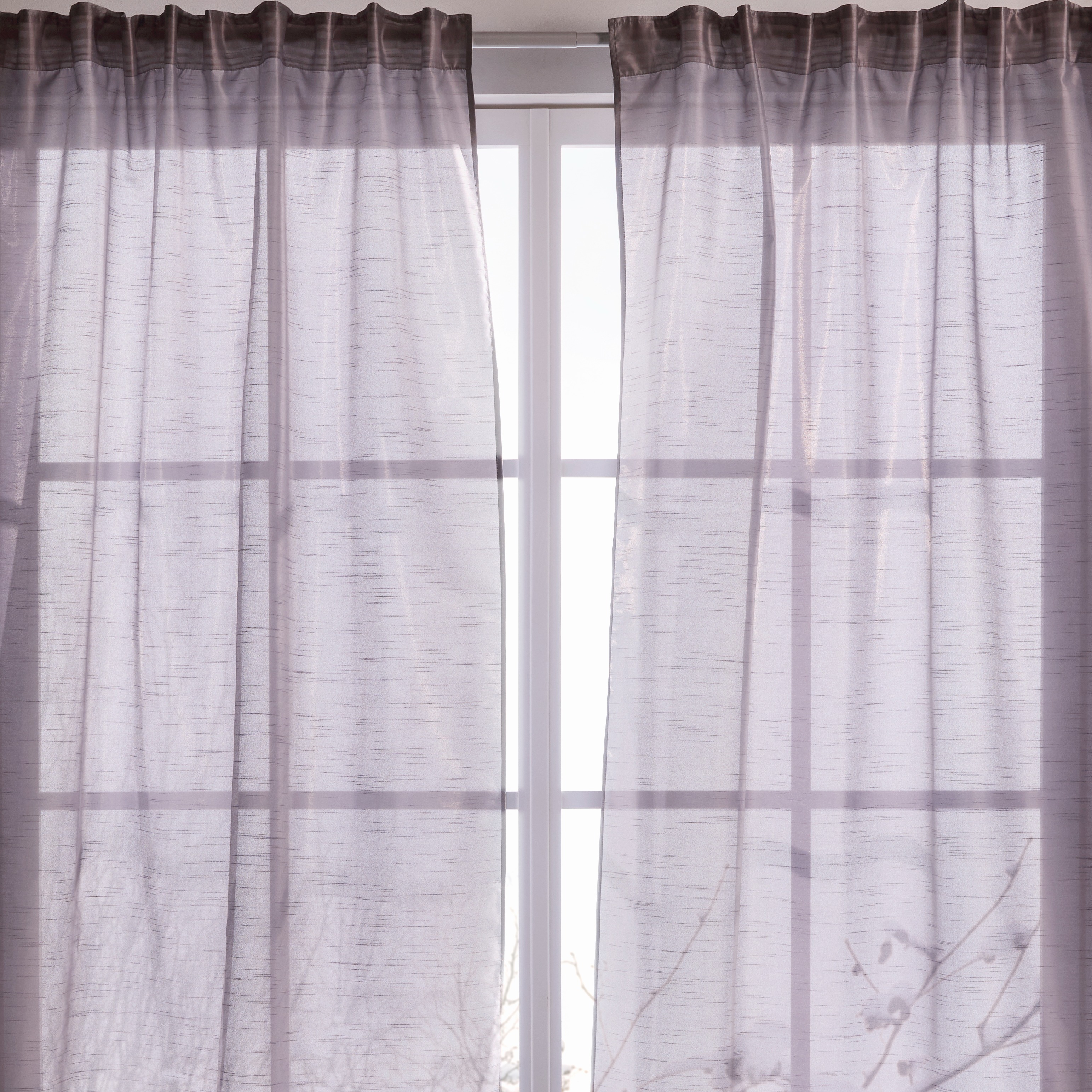 Luftige graue Vorhänge schmücken das Fenster.