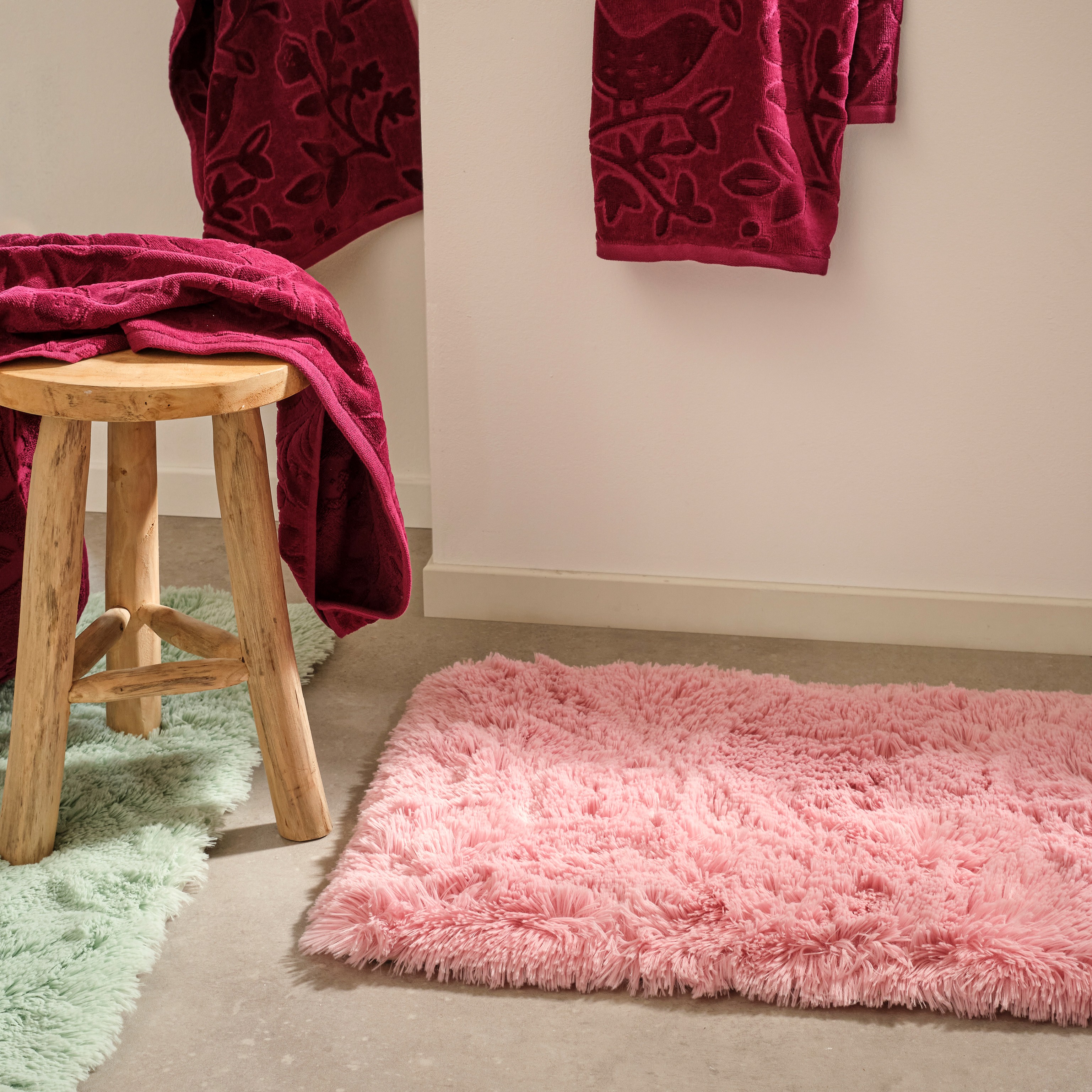 Weiche Badematte und rote Handtücher im Badezimmer.