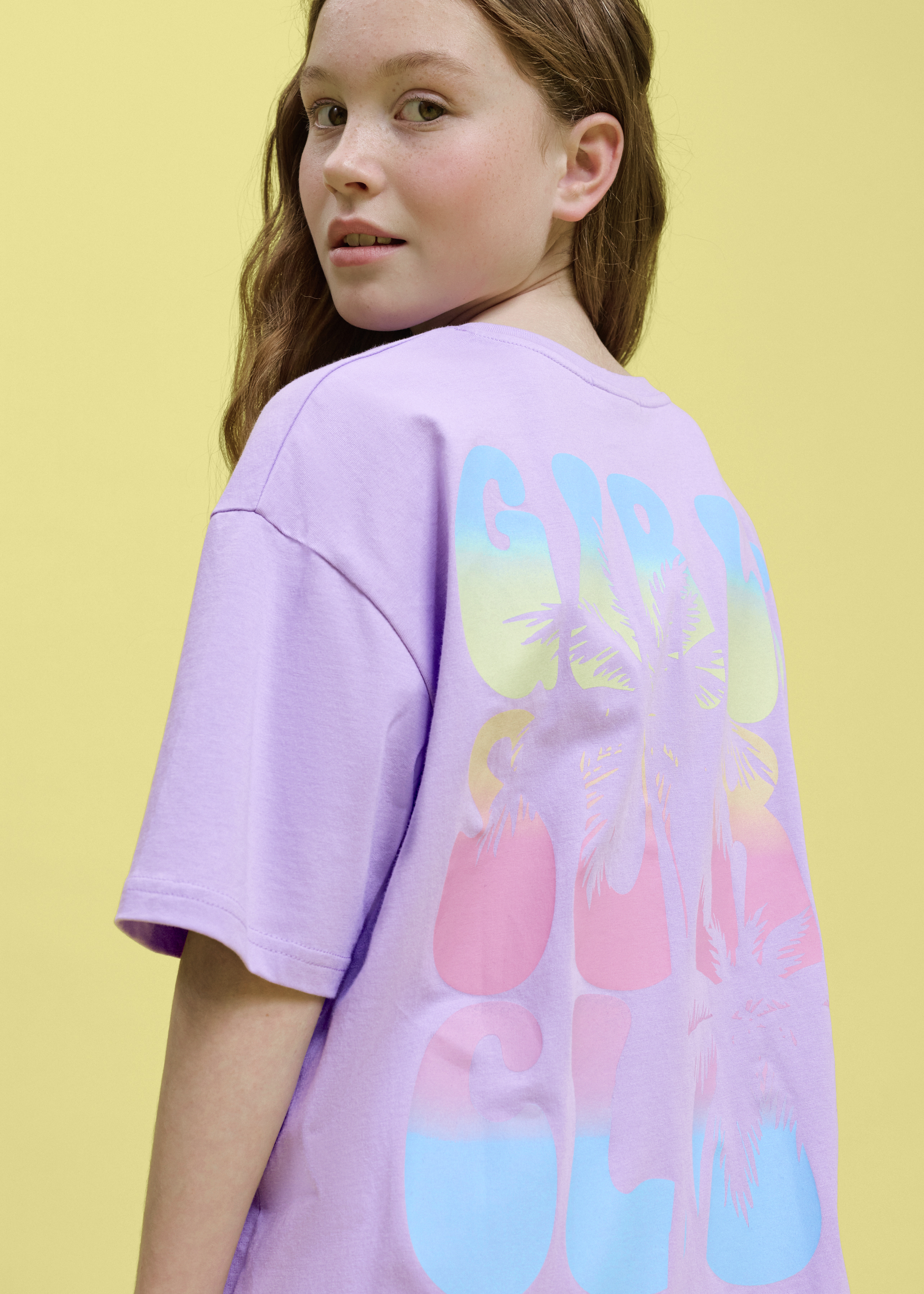 Ein lila Oversize-Shirt mit bunter Aufschrift auf dem Rücken.
