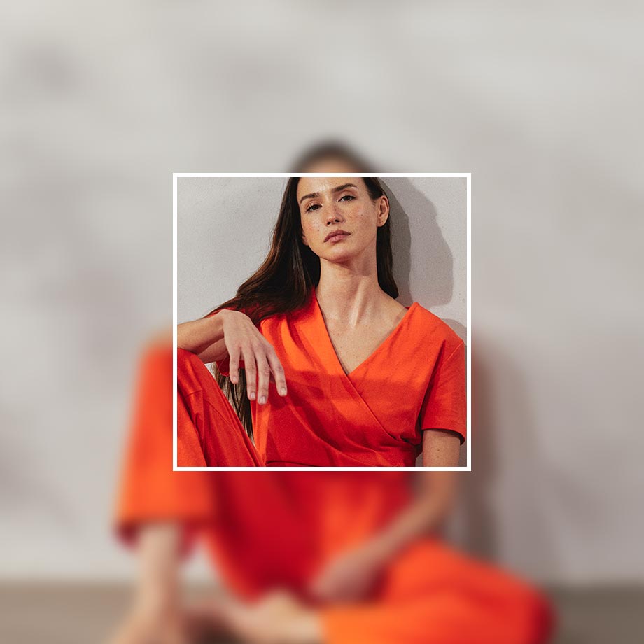 Leuchtendes Orange dominiert das Outfit. Ein elegantes, fließendes Kleid mit V-Ausschnitt betont die Silhouette.