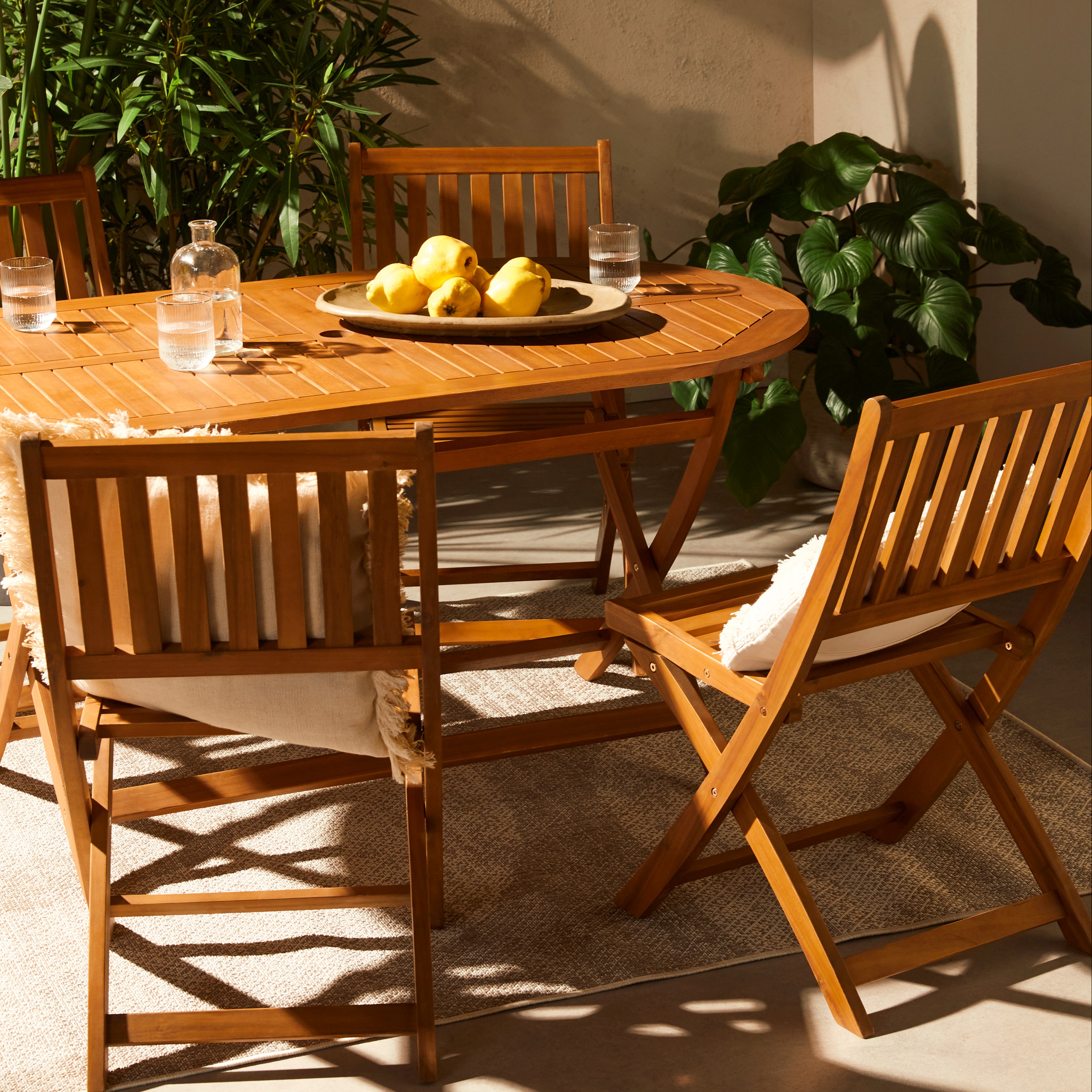 Garten-Set aus einem ovalen Holztisch und passenden Stühlen in Szene gesetzt.