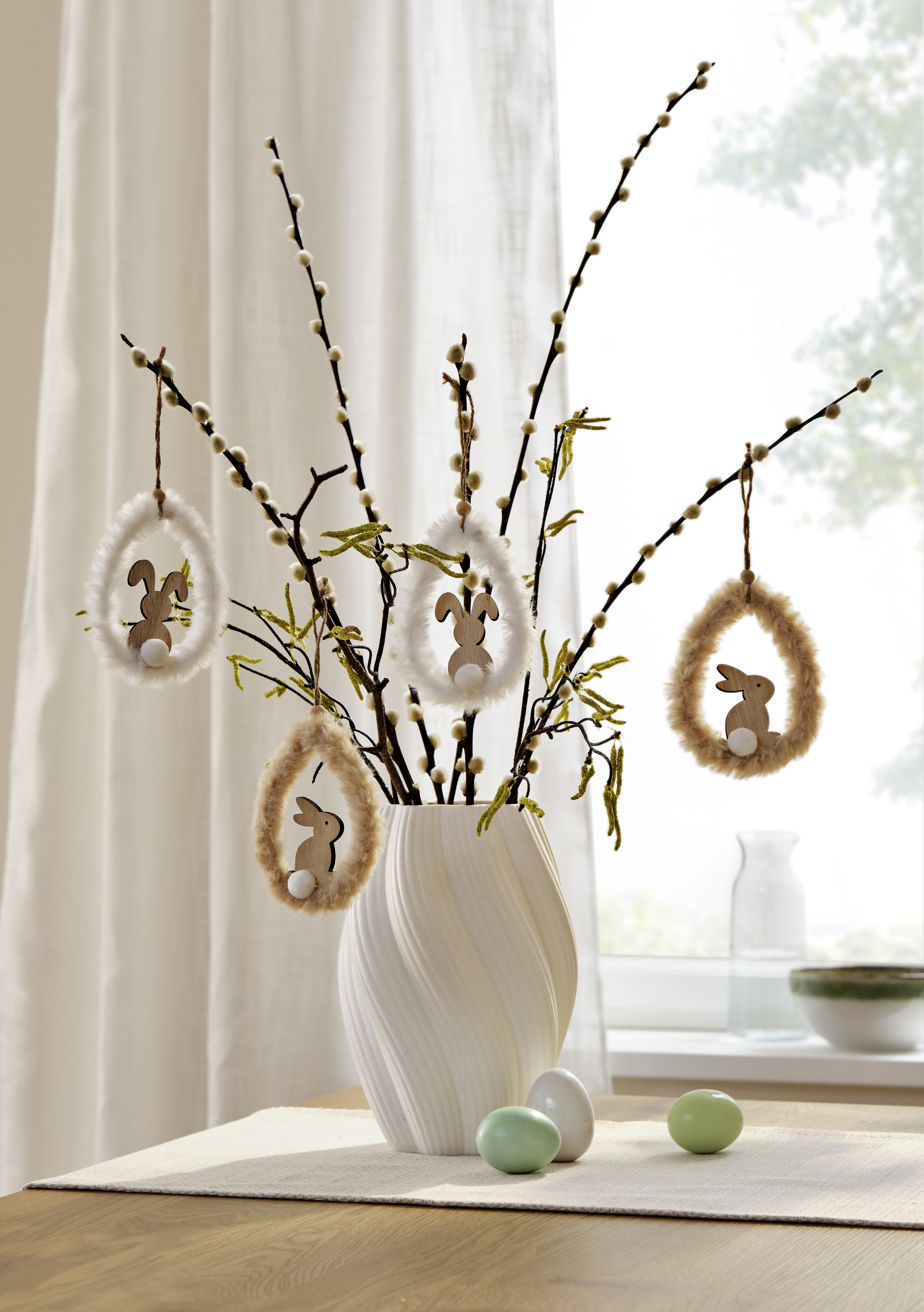 Österliche Dekoration mit Zweigen in weißer Vase.