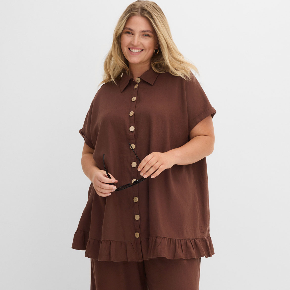 Braune Bluse mit Knopfleiste und Rüschensaum.