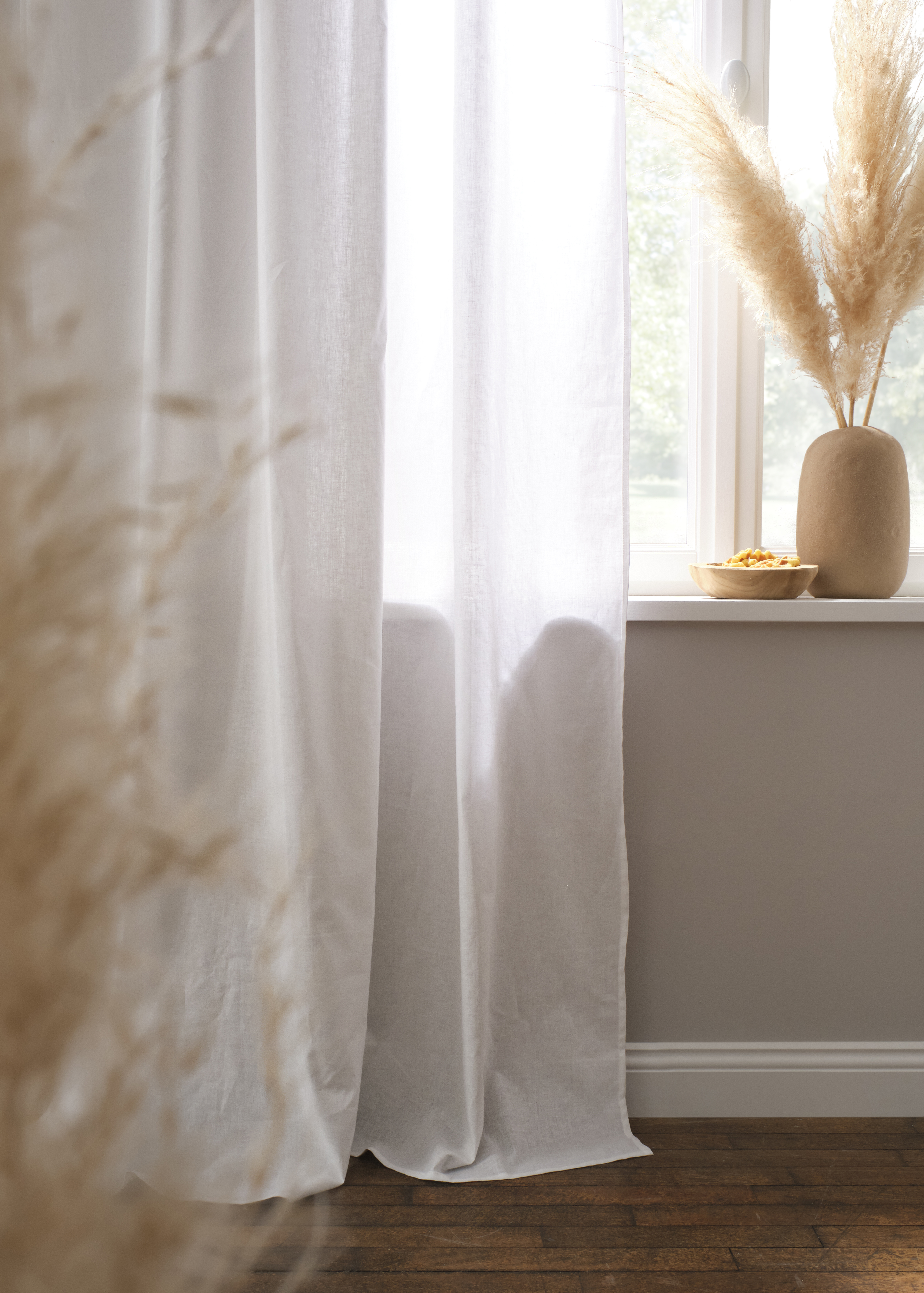 Leichte, weiße Vorhänge fallen elegant zu Boden.
