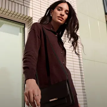 Dunkler Cardigan, elegante schwarze Tasche und dezenter Schmuck für einen stilvollen Look.