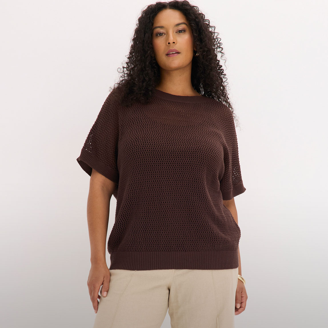 Brauner Oversize-Pullover und eine helle Hose.