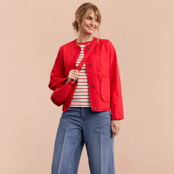 Rote Jacke über gestreiftem Shirt, weite Jeans und rote Sneakers.