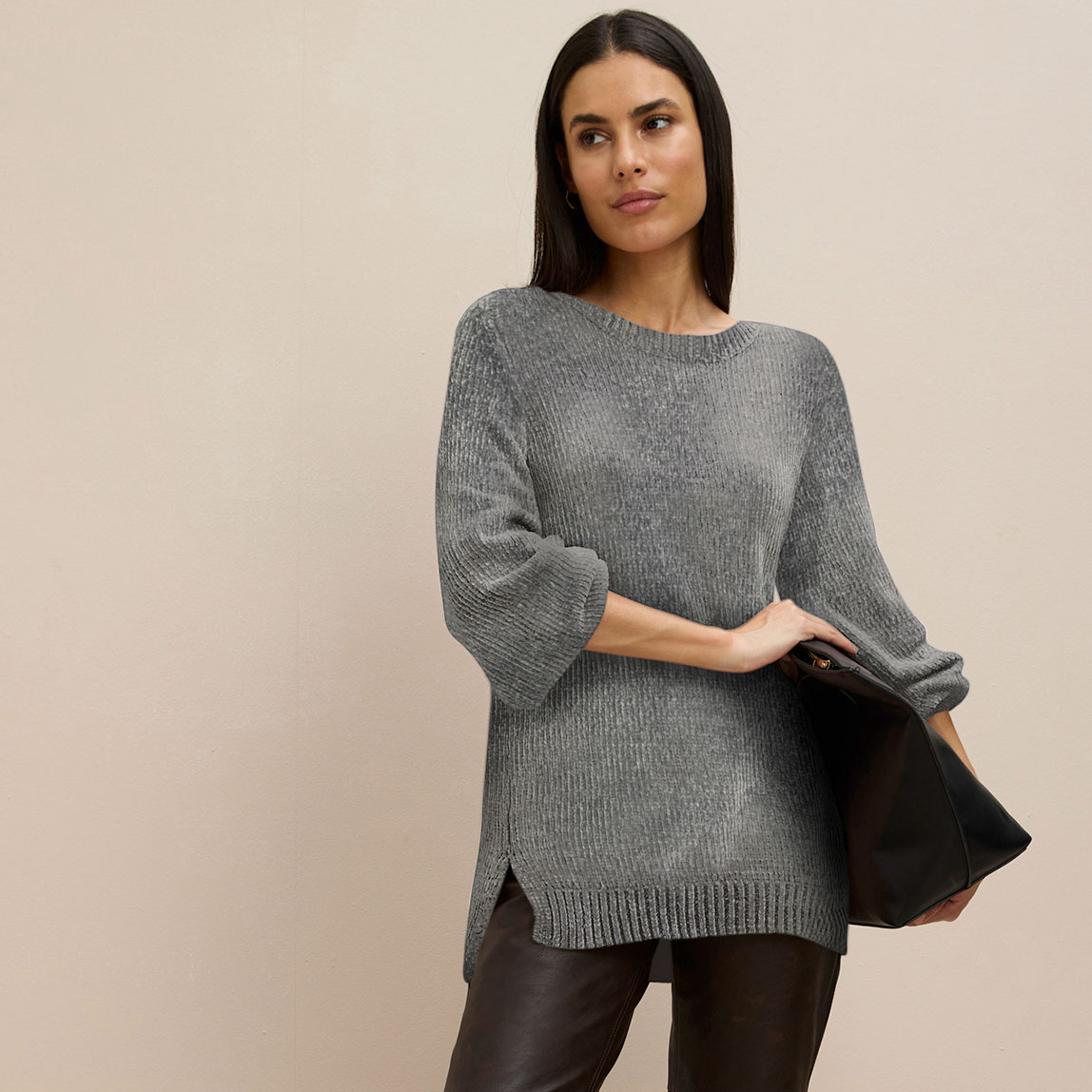 Grauer Longpullover kombiniert mit dunkler Hose.