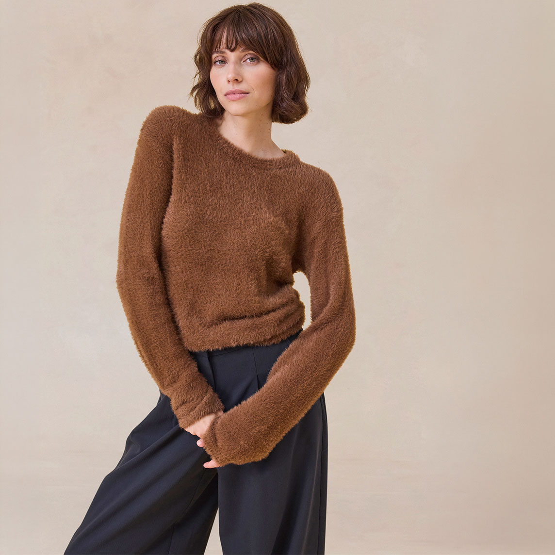 Brauner, flauschiger Pullover und weite, dunkle Hose – stilvoll und bequem.