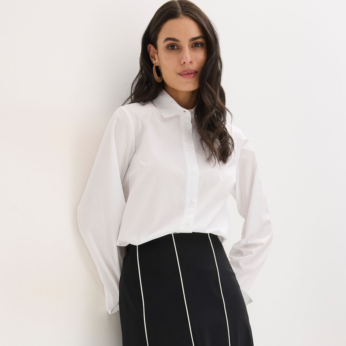 Weiße Bluse mit Kragen und schwarz-weißer Rock mit vertikalen Streifen.