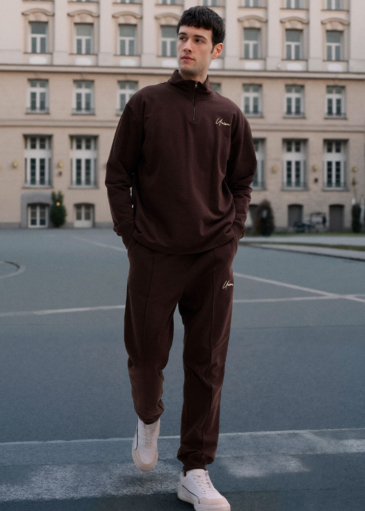 Dunklelbrauner Trainingsanzug  weiße Sneaker.