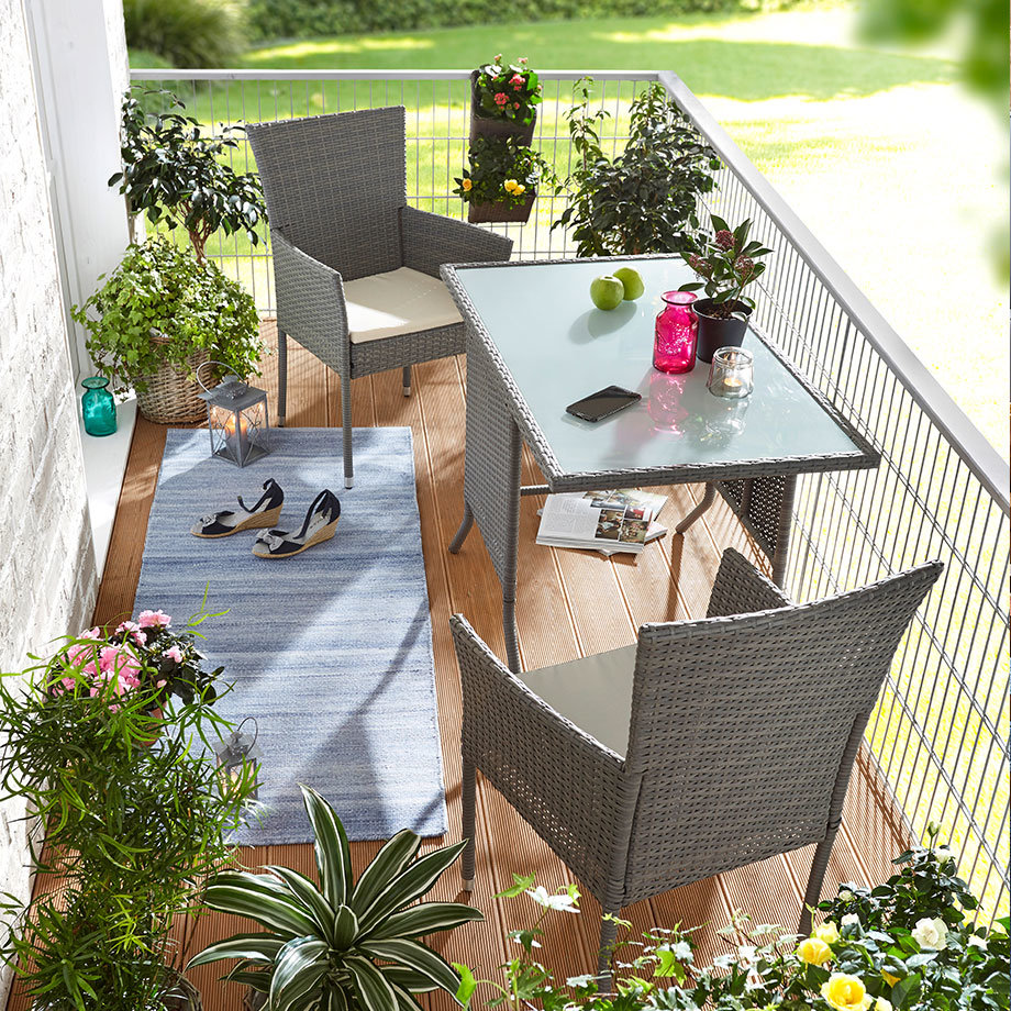 Gemütliche Rattan-Stühle und ein Glastisch laden zum Entspannen auf dem sonnigen Balkon ein.
