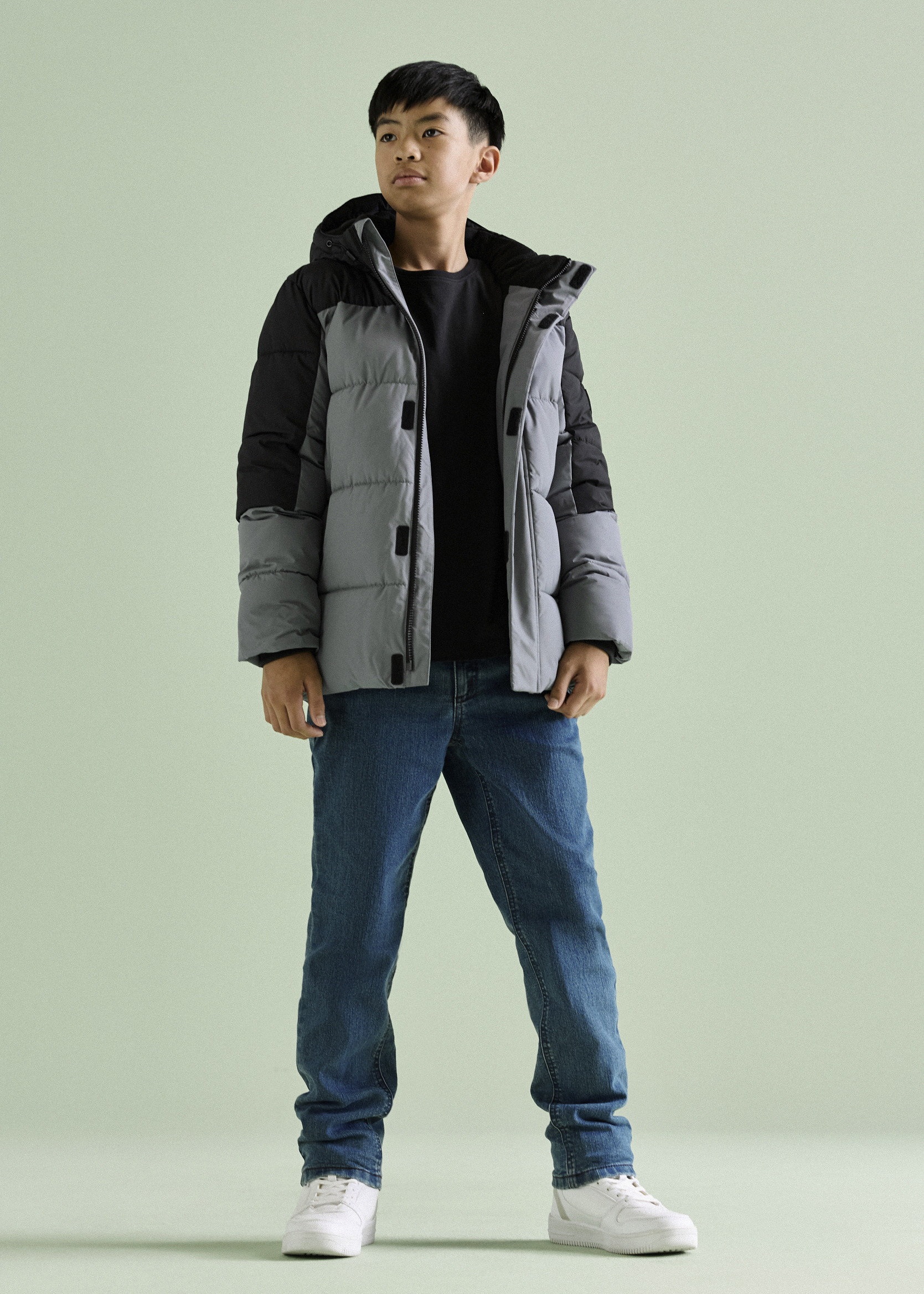 Junge trägt grau-schwarze Winterjacke.