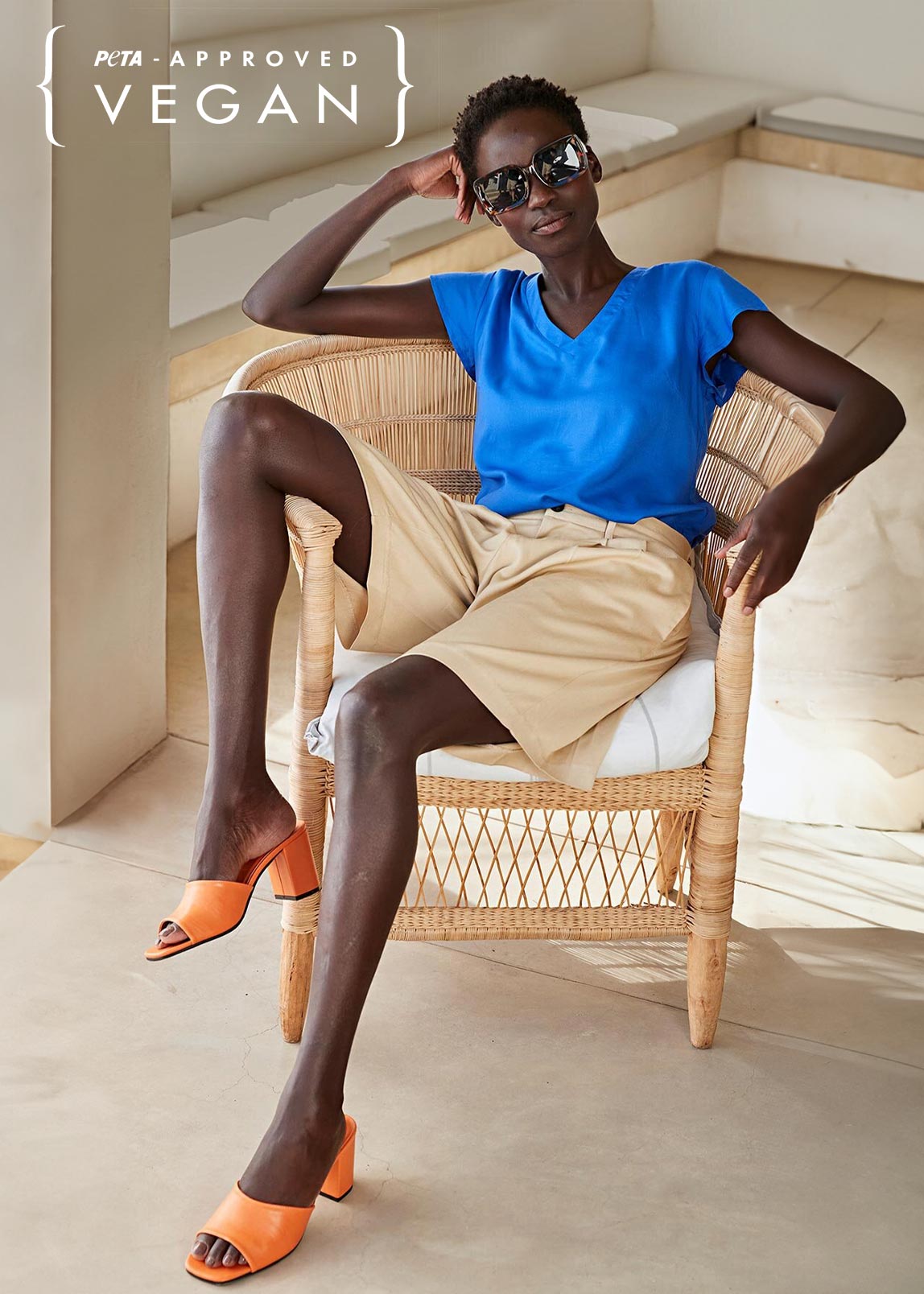Sommerlicher Look: Blaues T-Shirt, beige Shorts und orange Sandalen. Vegane Mode für warme Tage.