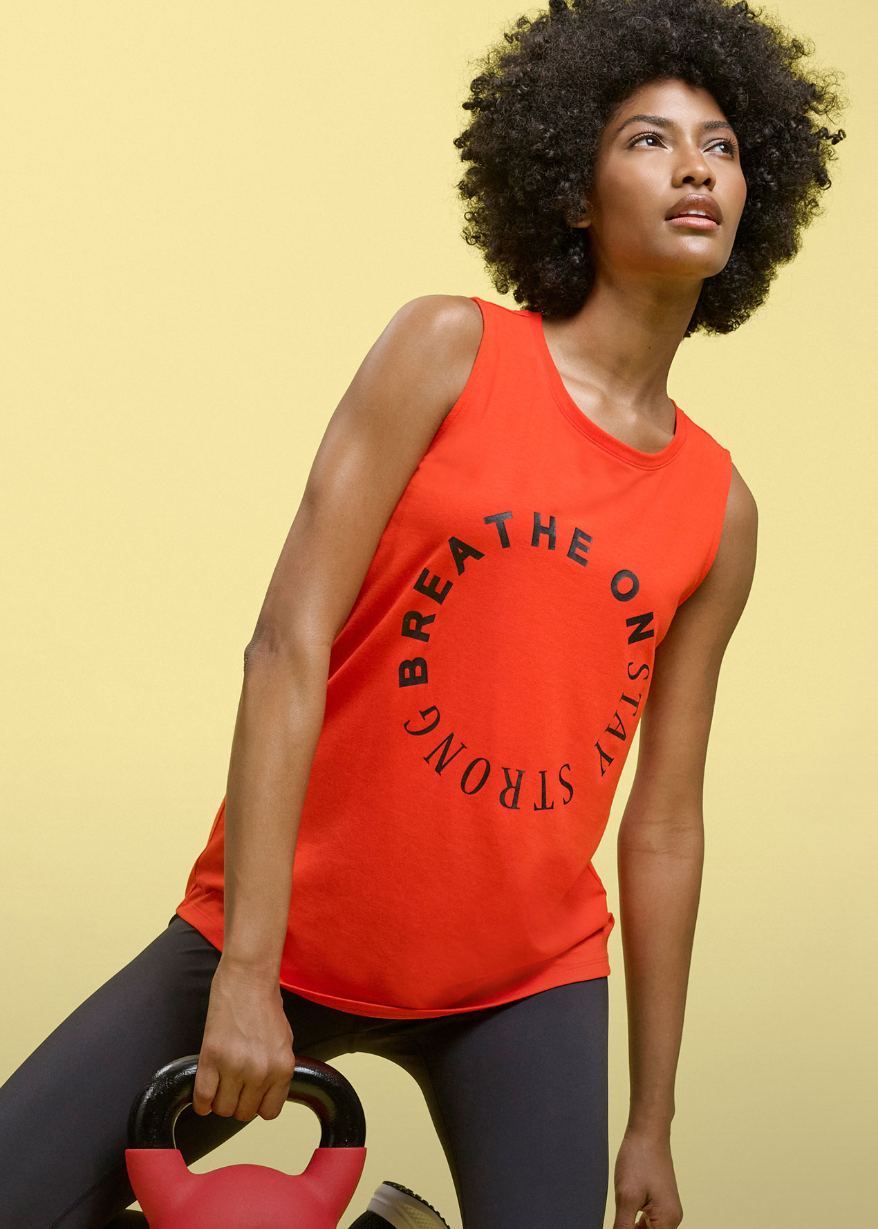 Rotes ärmelloses Oberteil mit Schriftzug und dunkle Sportleggings für das Training.
