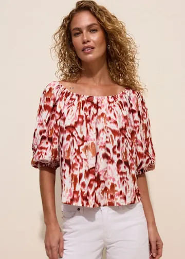 Carmen-Bluse mit lebhaftem Muster und bequeme weiße Jeans.