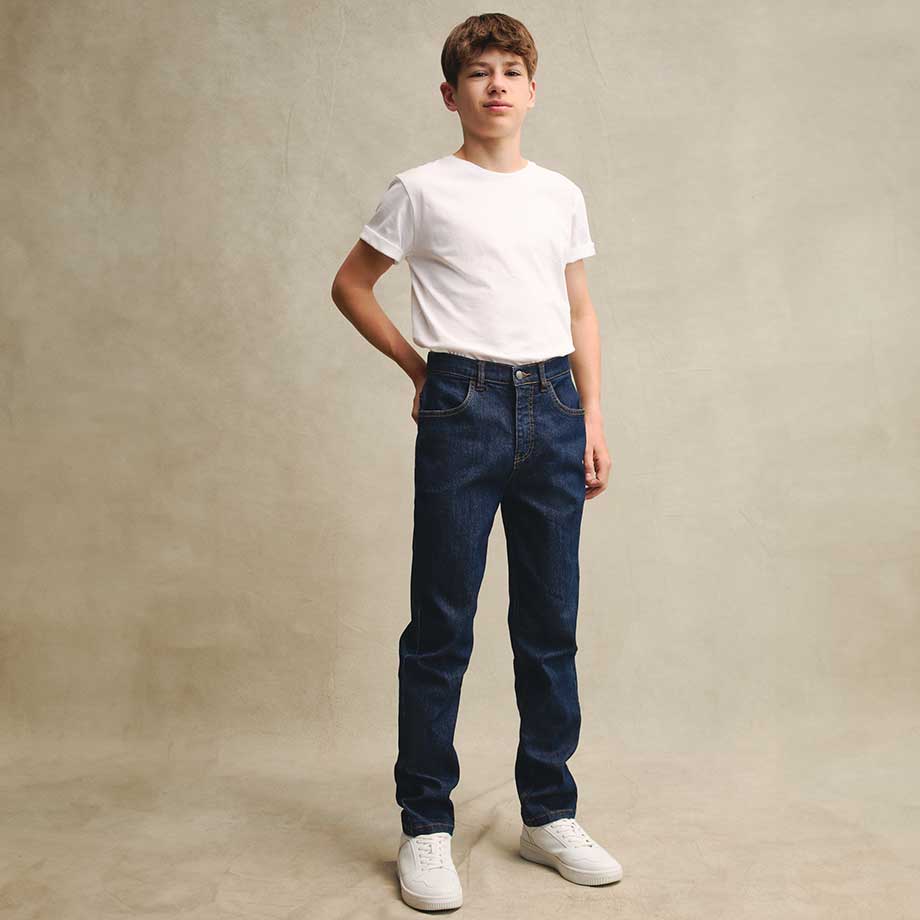 Schlichtes weißes T-Shirt kombiniert mit klassischen dunkelblauen Jeans und weißen Sneakern.