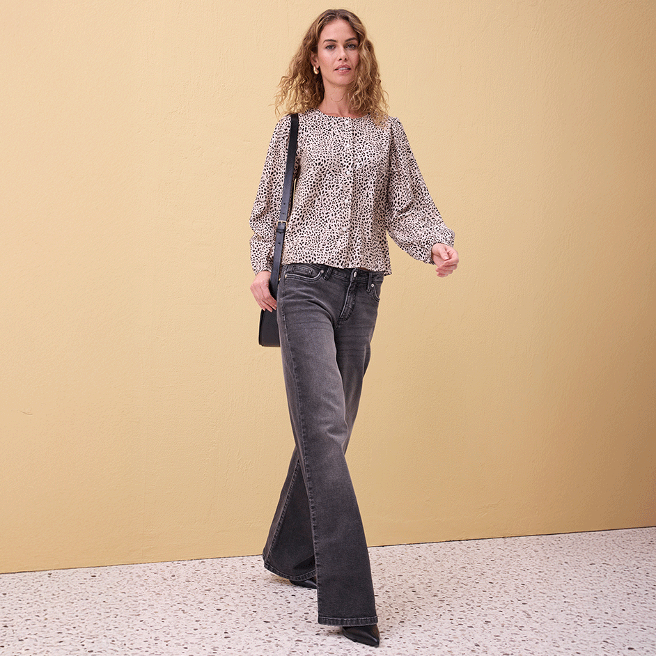 Luftige gemusterte Bluse mit Puffärmeln, kombiniert mit ausgestellter grauer Jeans.