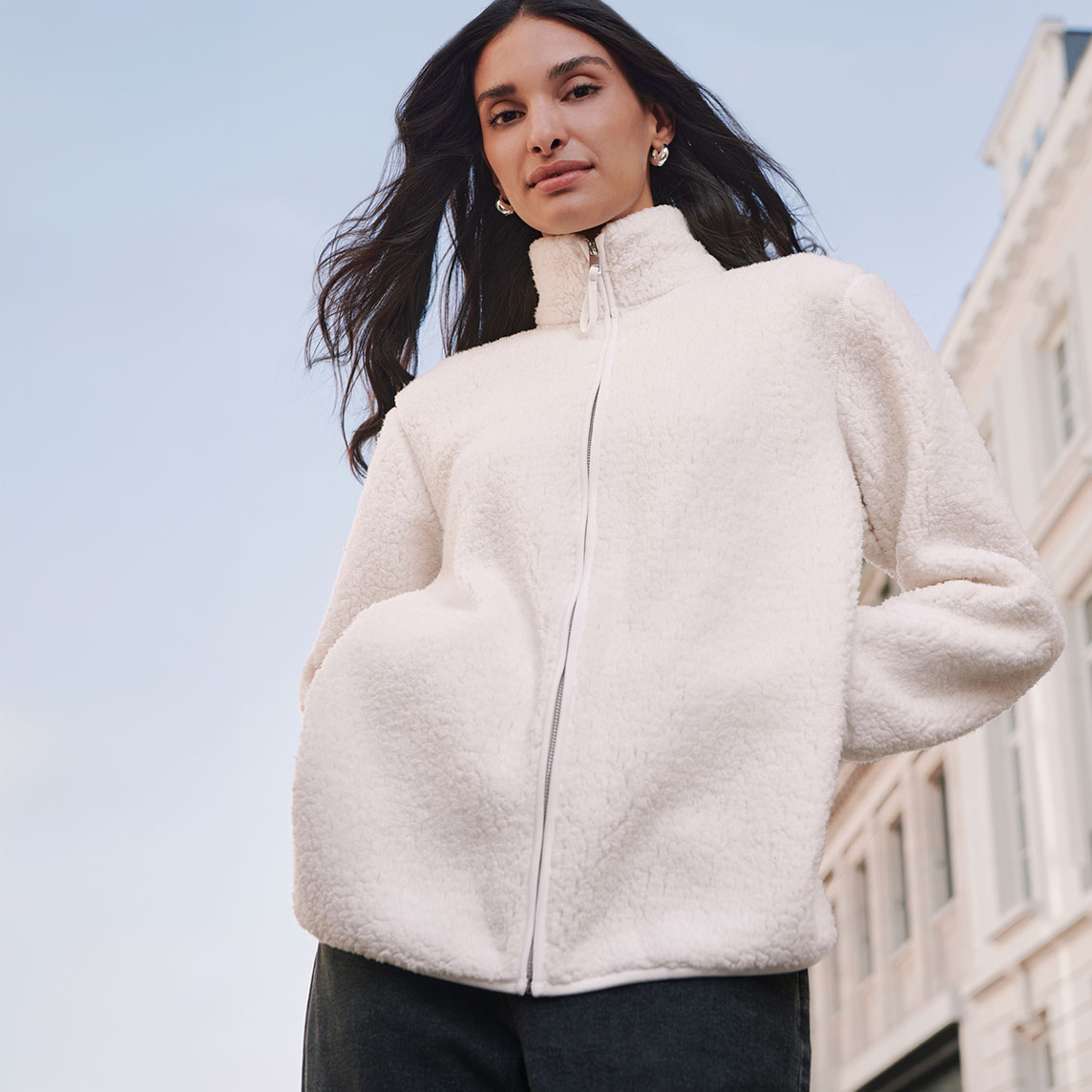 Flauschige, cremefarbene Teddyfell-Jacke mit Reißverschluss und modischer dunkler Hose.