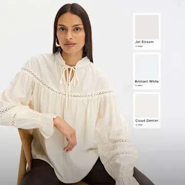 Elegante, bestickte Bluse in Cremeweiß, perfekt abgestimmt auf die gezeigten Weißtöne.