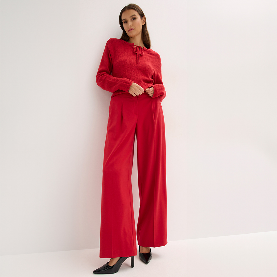 Stilvoller roter Zweiteiler mit weiten Hosen und eleganten schwarzen Pumps.