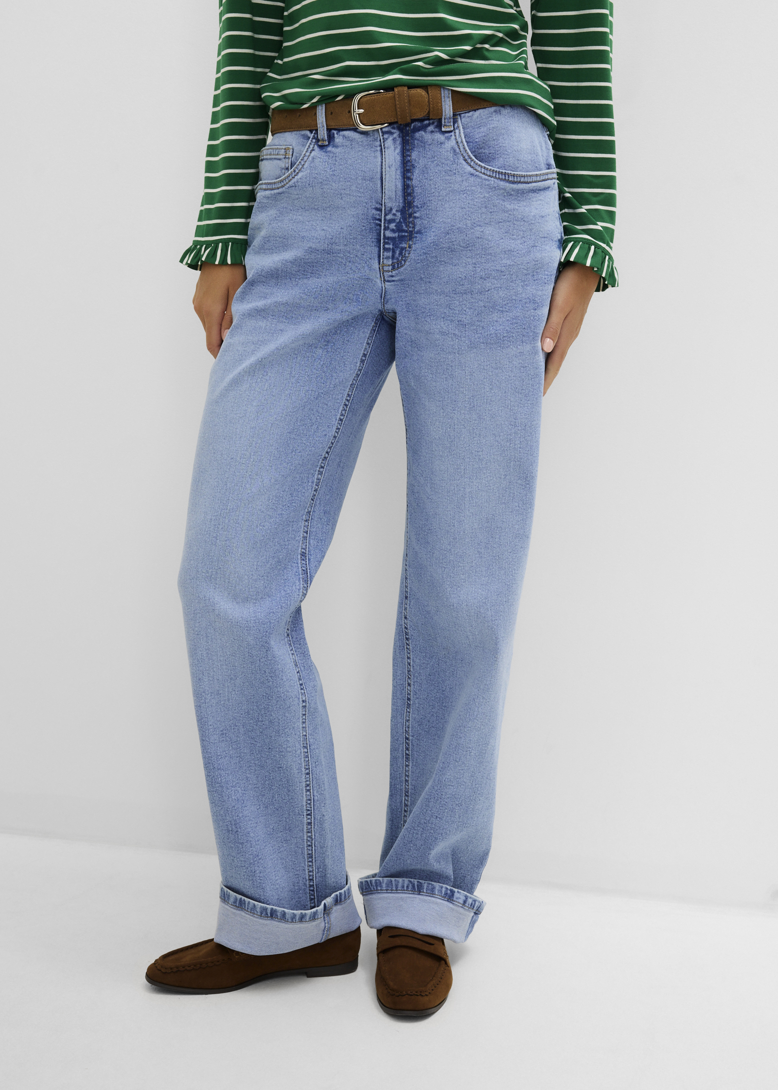 Modisches Outfit: Gestreiftes Shirt, weite hellblaue Jeans, brauner Gürtel und braune Wildleder-Loafer.