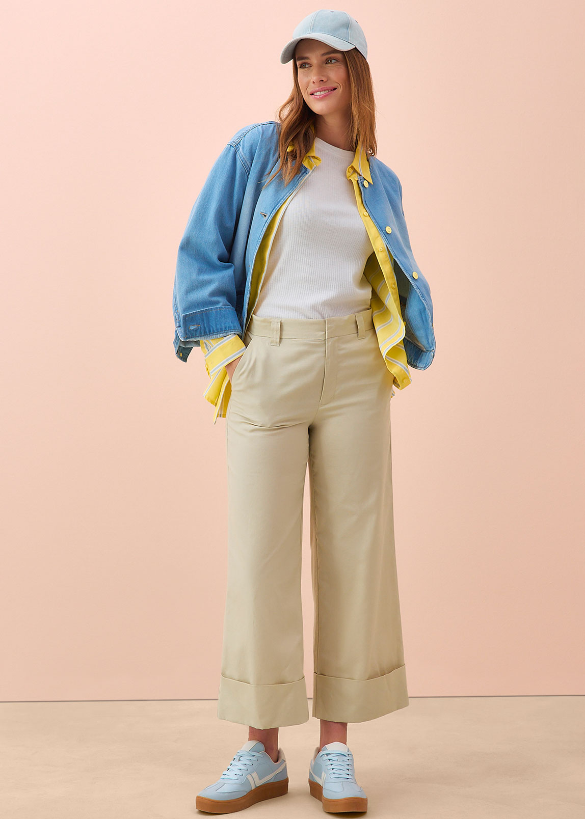 Frühlingsoutfit mit Jeansjacke, weißem Shirt, beiger Culotte-Hose und hellblauen Sneakers.