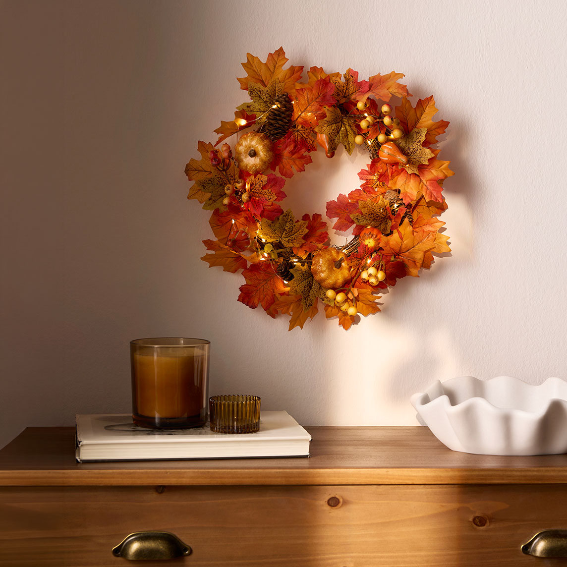 Ein Kranz mit herbstlicher Dekoration und LED-Lichtern.