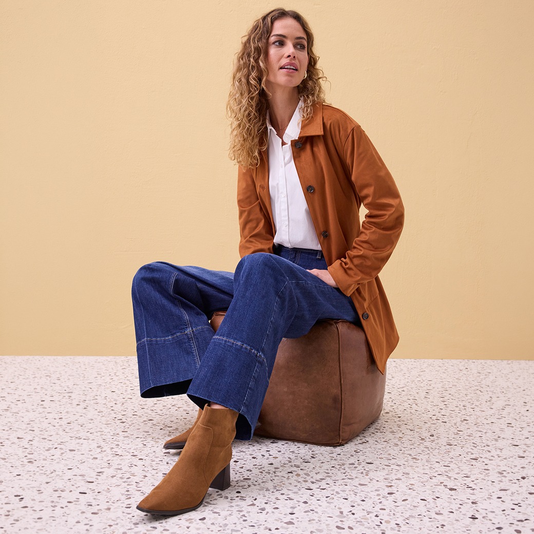 Cognacfarbener Mantel, weiße Bluse, weite Jeans und braune Stiefeletten.