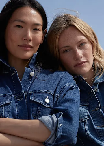 Zwei Frauen tragen modische, blaue Jeansjacken.