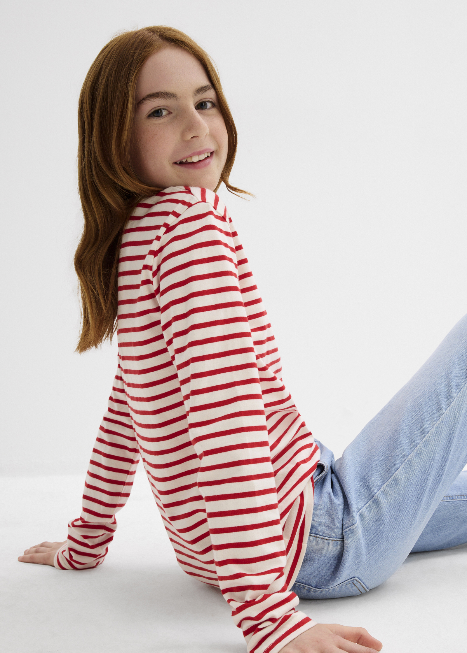 Das Mädchen trägt ein rot-weiß gestreiftes Langarmshirt.