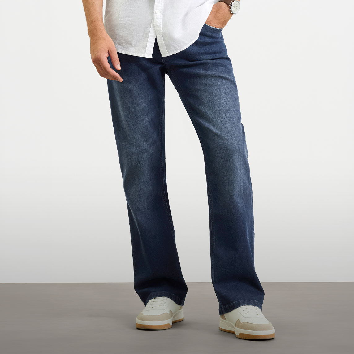 Lässige Regular-Fit Jeans und weißes Hemd, kombiniert mit modernen Sneakern.