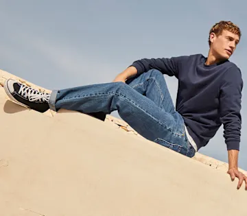 Schlichtes blaues Sweatshirt, klassische Jeans und Sneaker.