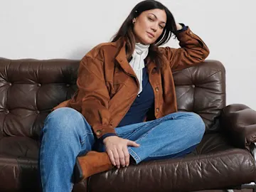 Jacke in Wildlederoptik, blaue Jeans, dunkles Oberteil, heller Schal und Stiefel.