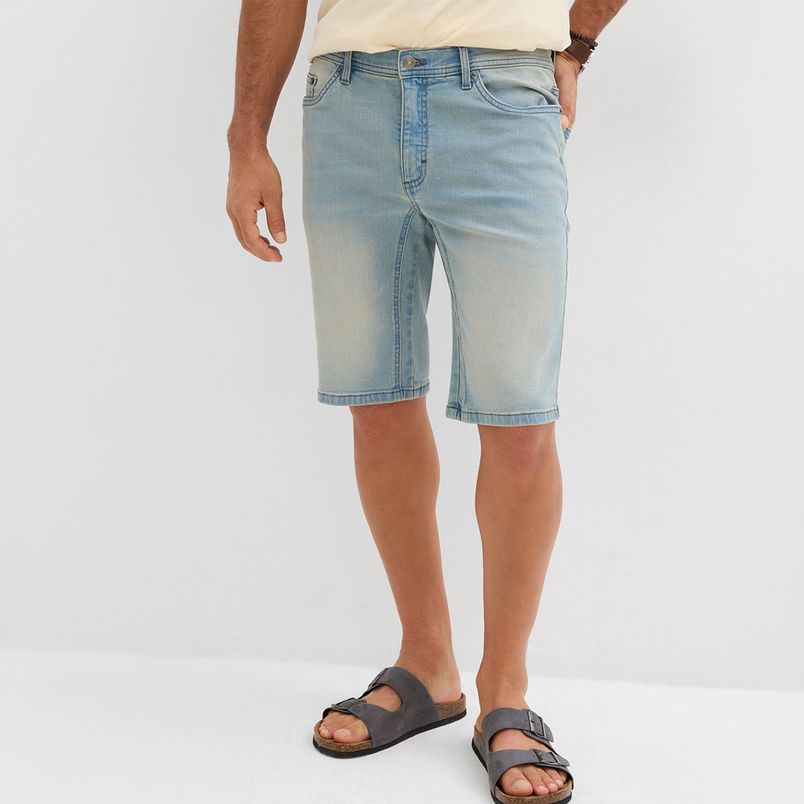 Helle Jeans-Shorts in entspannter Passform, kombiniert mit dunklen Sandalen für einen lässigen Sommerlook.