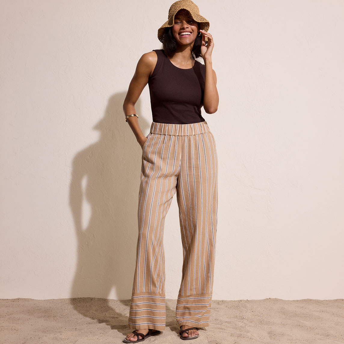 Schwarzes Top kombiniert mit luftigen, gestreiften Hosen in warmen Erdtönen für einen lässigen Sommerlook.