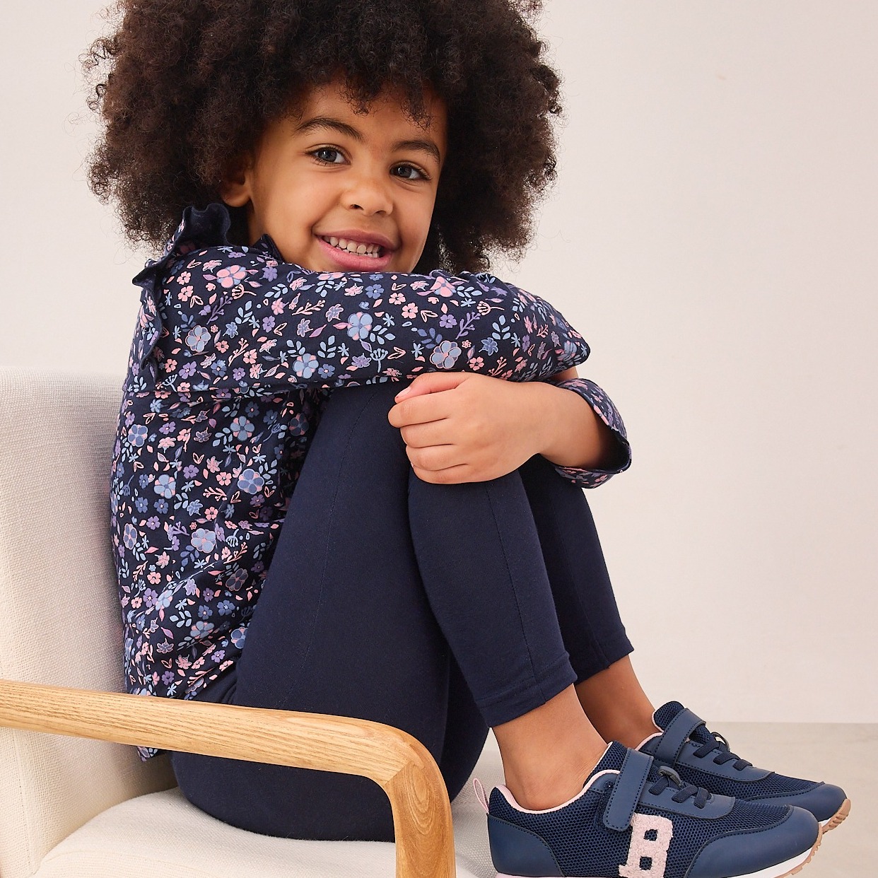 Blau dominiert das Outfit: gemustertes Oberteil, einfarbige Hose und sportliche Schuhe harmonieren perfekt.