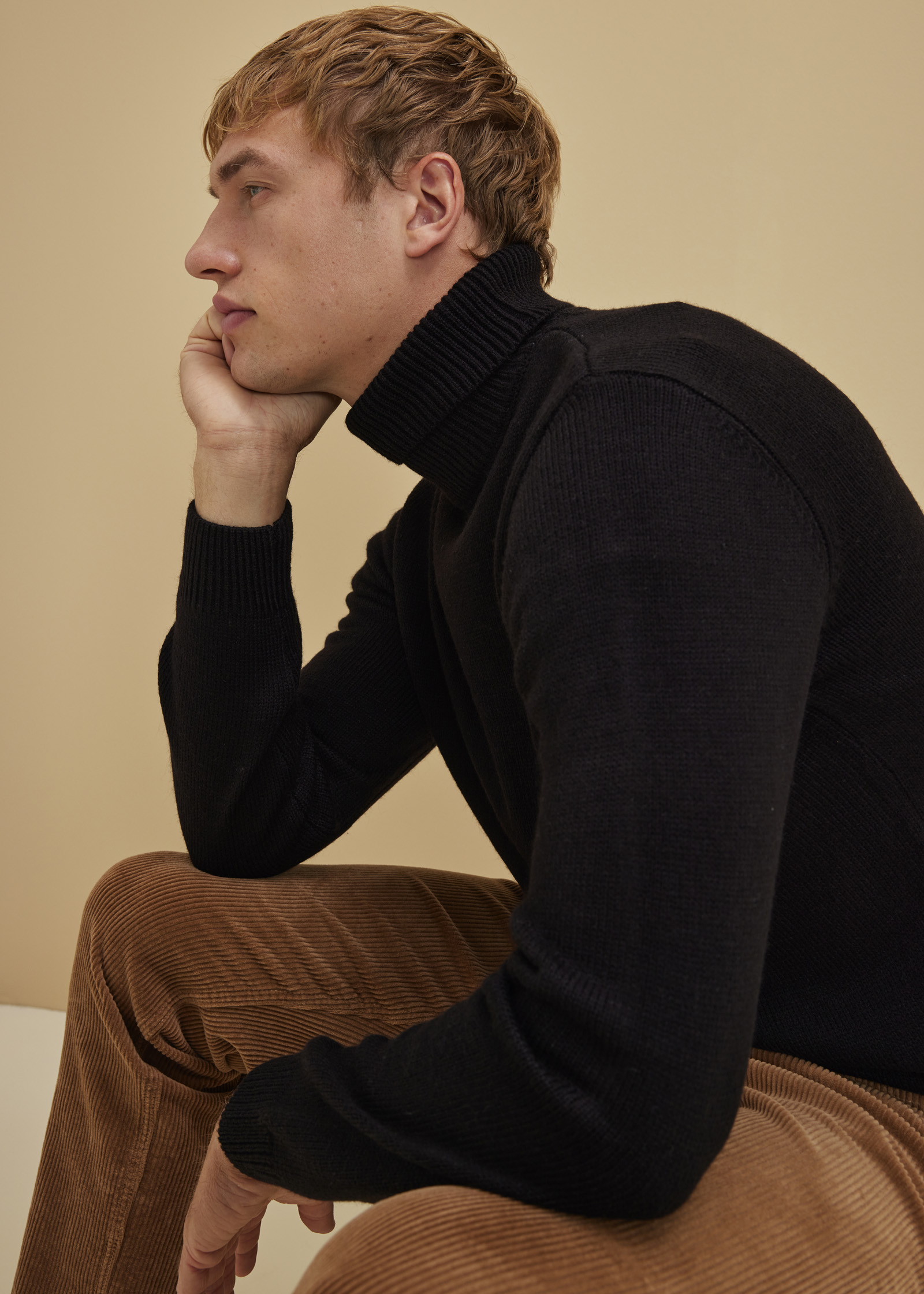 Schwarzer Rollkragenpullover und braune Cordhose bilden ein stilvolles Outfit.