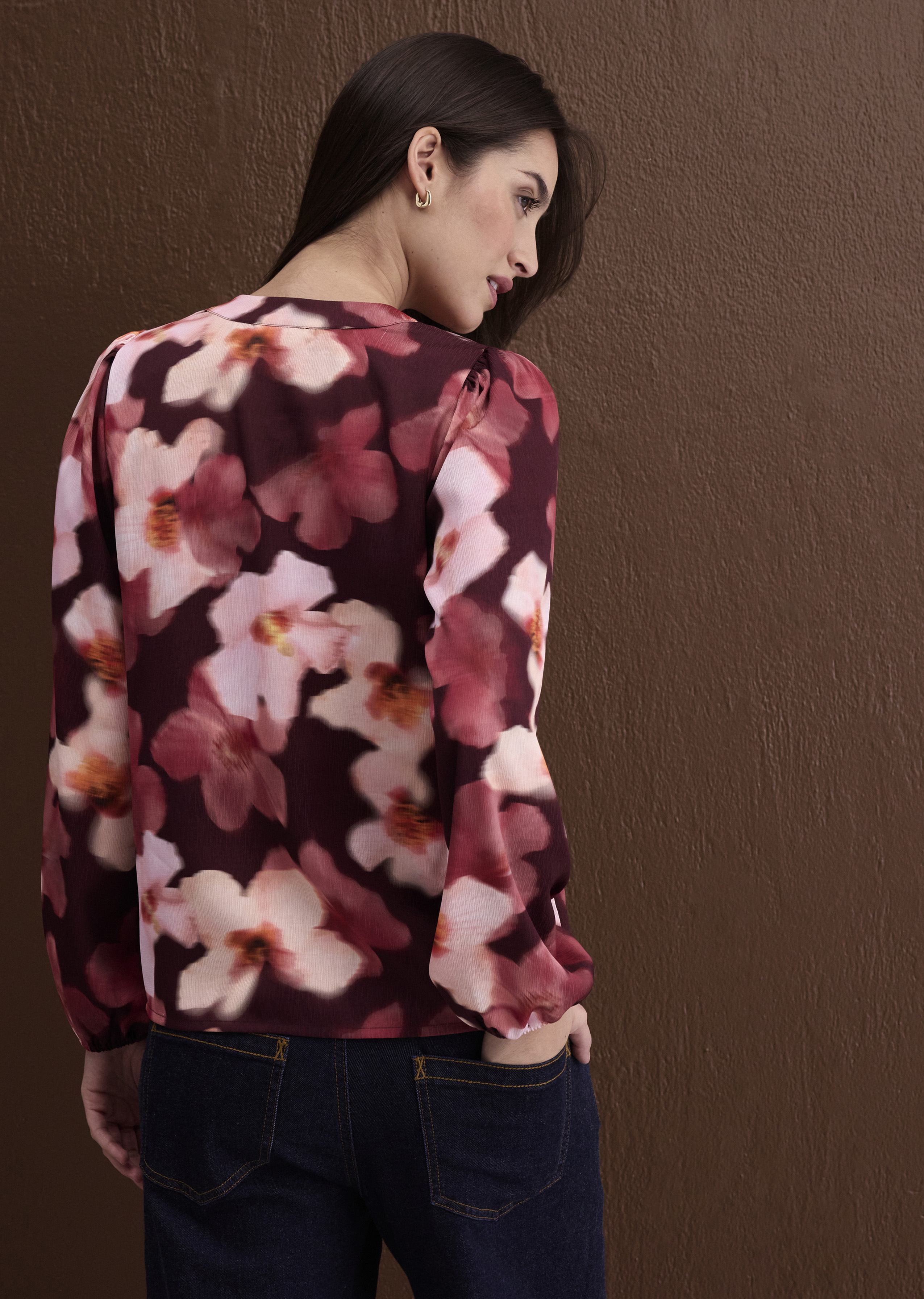 Dunkelrote Blumenbluse mit zarten Blüten, kombiniert mit klassischen blauen Jeans.