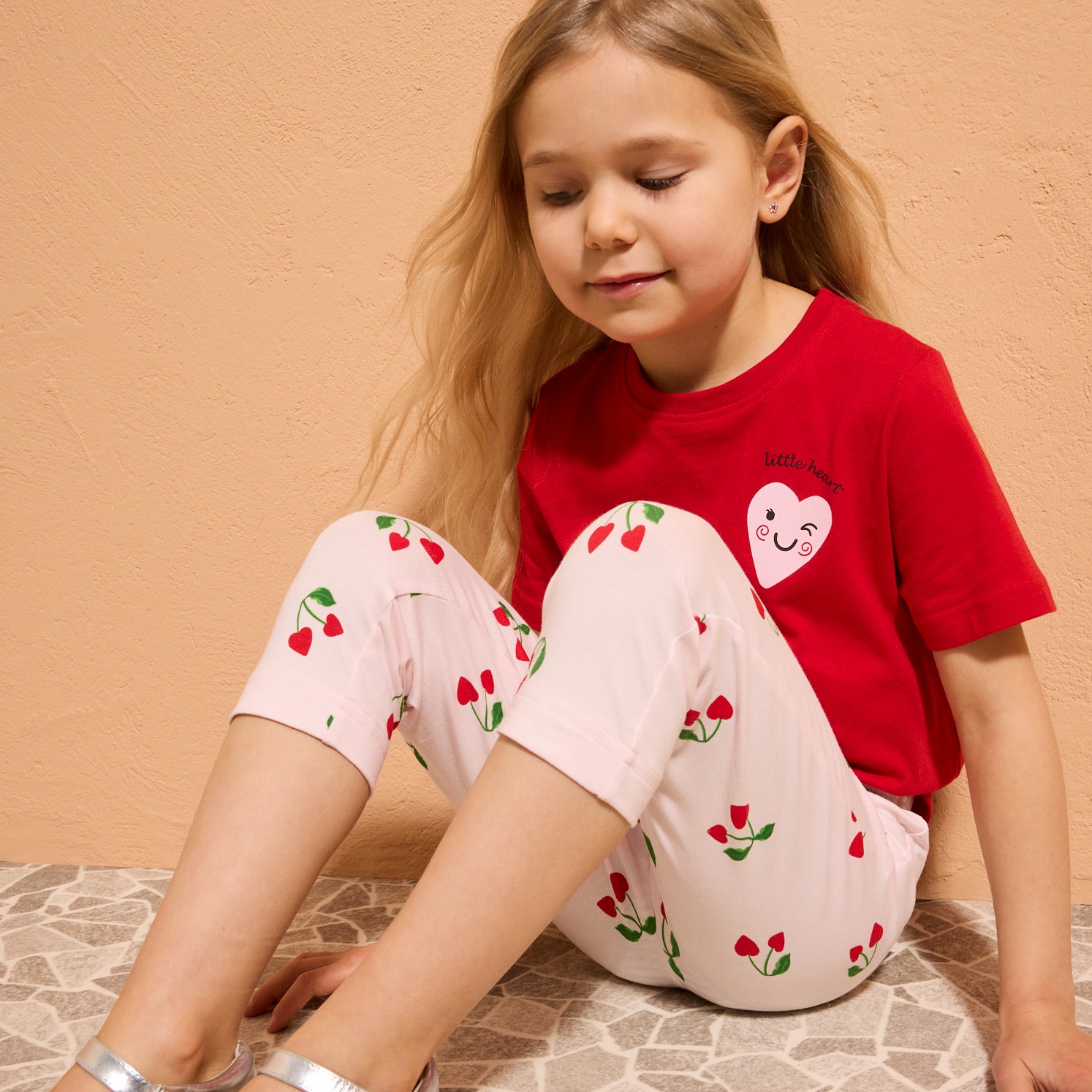 Ein kleines Mädchen trägt ein rotes T-Shirt mit Herz-Motiv.