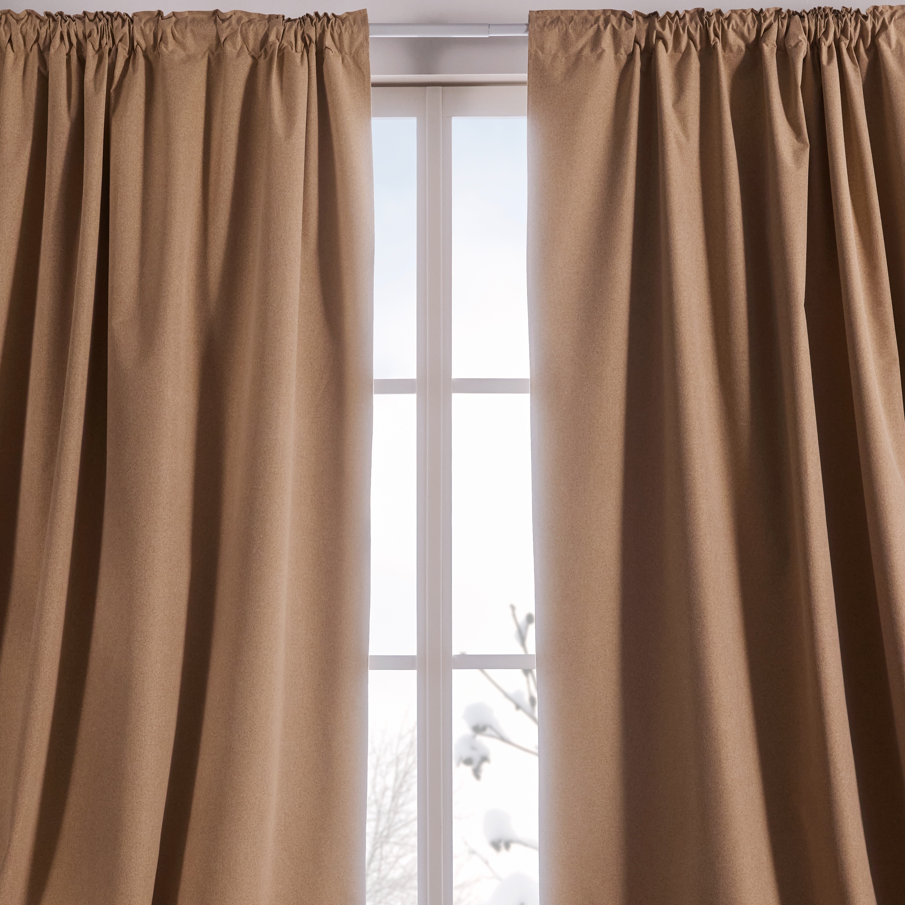 Elegante beige Vorhänge rahmen das helle Fenster ein.