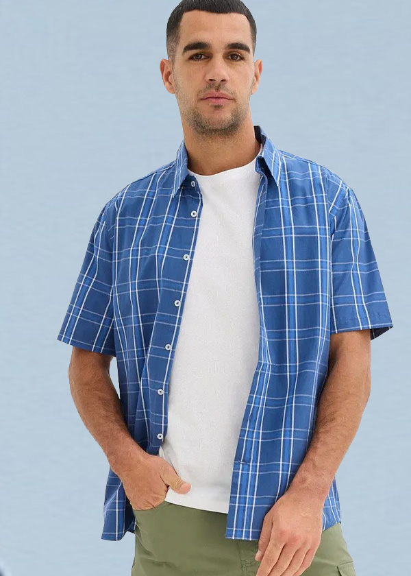 Kariertes blaues Kurzarmhemd, weißes Shirt und grüne Cargo-Shorts für einen entspannten Stil.