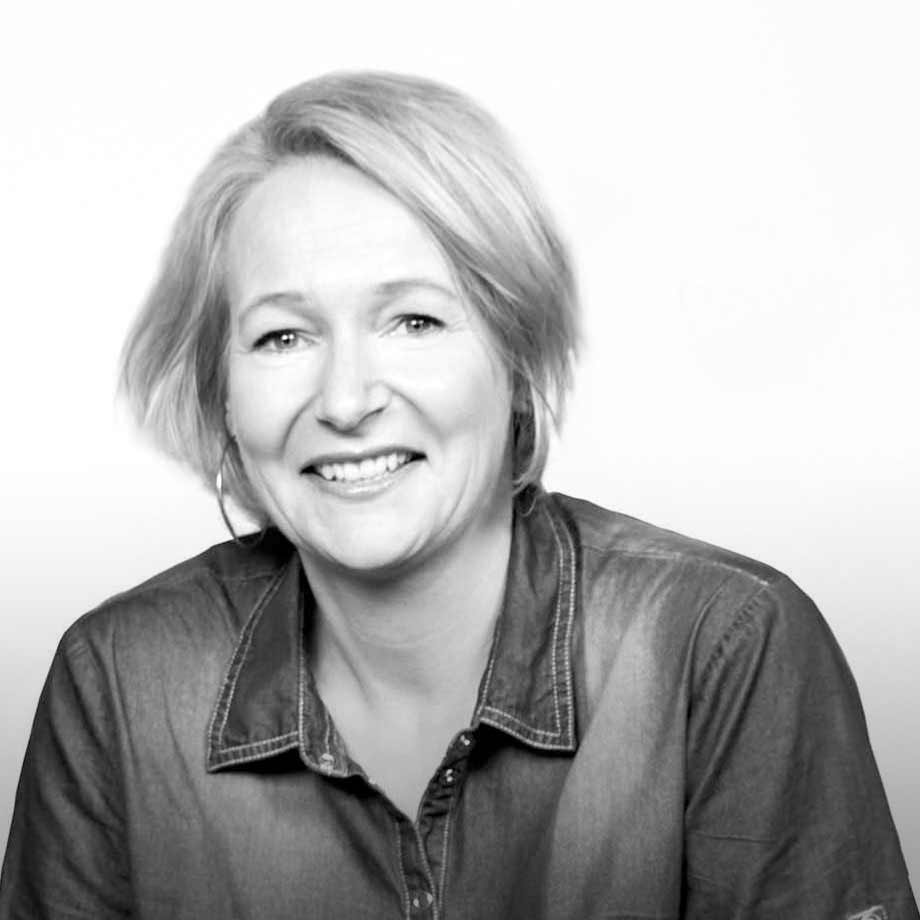 Lässiger Stil mit Jeanshemd. Helles Haar und freundliches Lächeln strahlen Wärme aus.