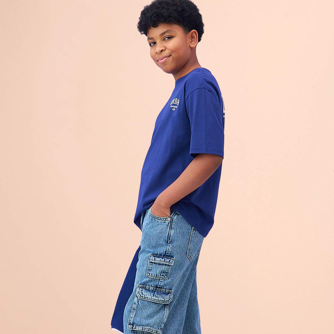 Blaues T-Shirt mit kleinem Logo und Jeans ergeben einen lässigen, jugendlichen Look.