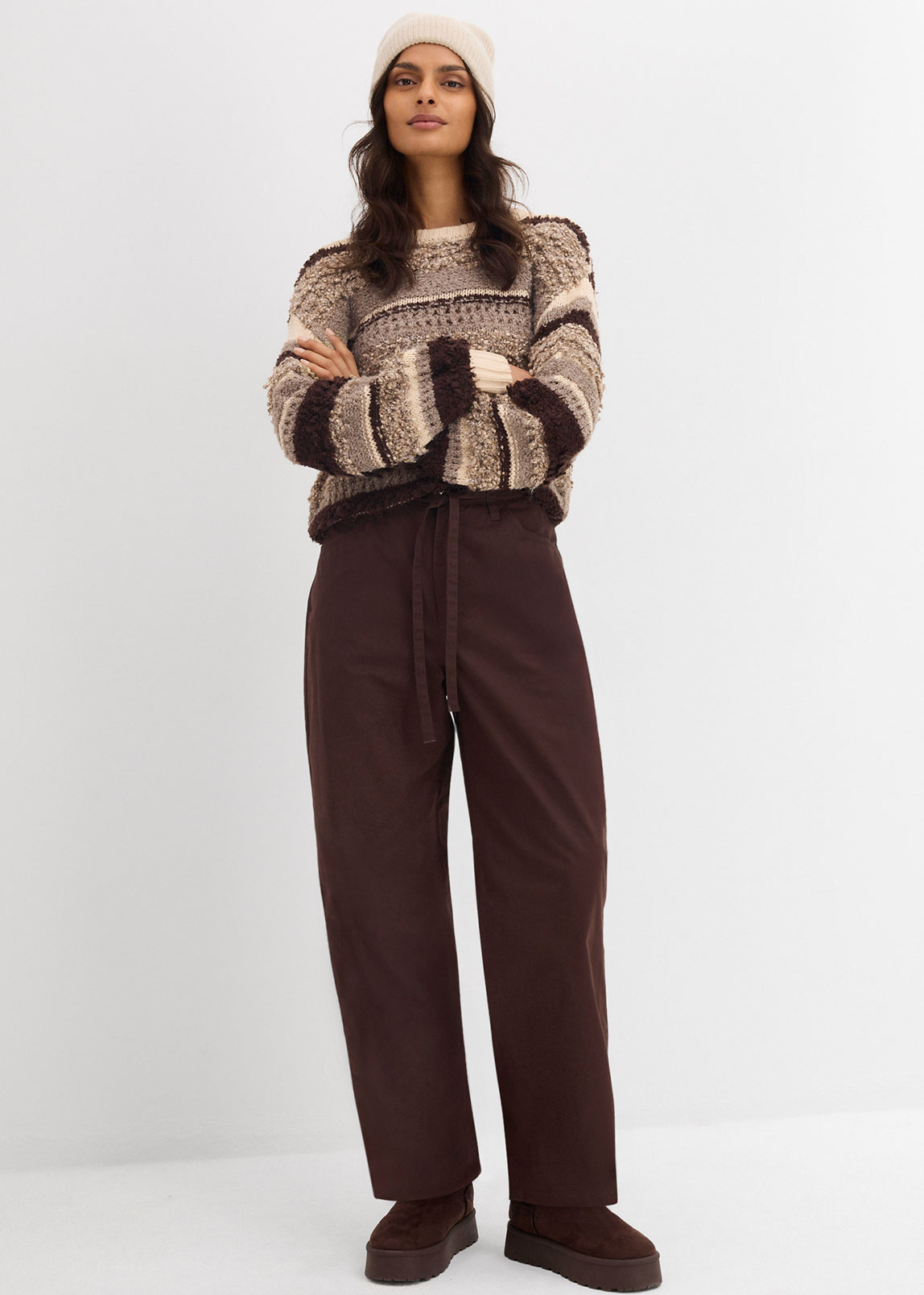 Strickpullover in Beige und Braun mit brauner Hose.