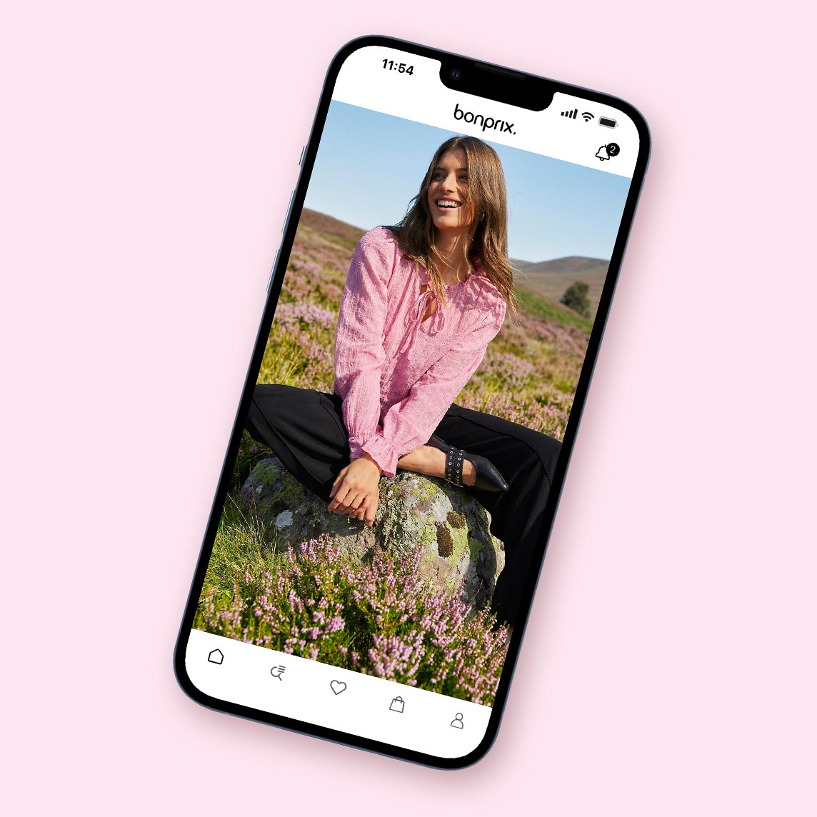 Eine rosa Bluse mit Knöpfen und Kragen kontrastiert mit einer dunklen Hose.